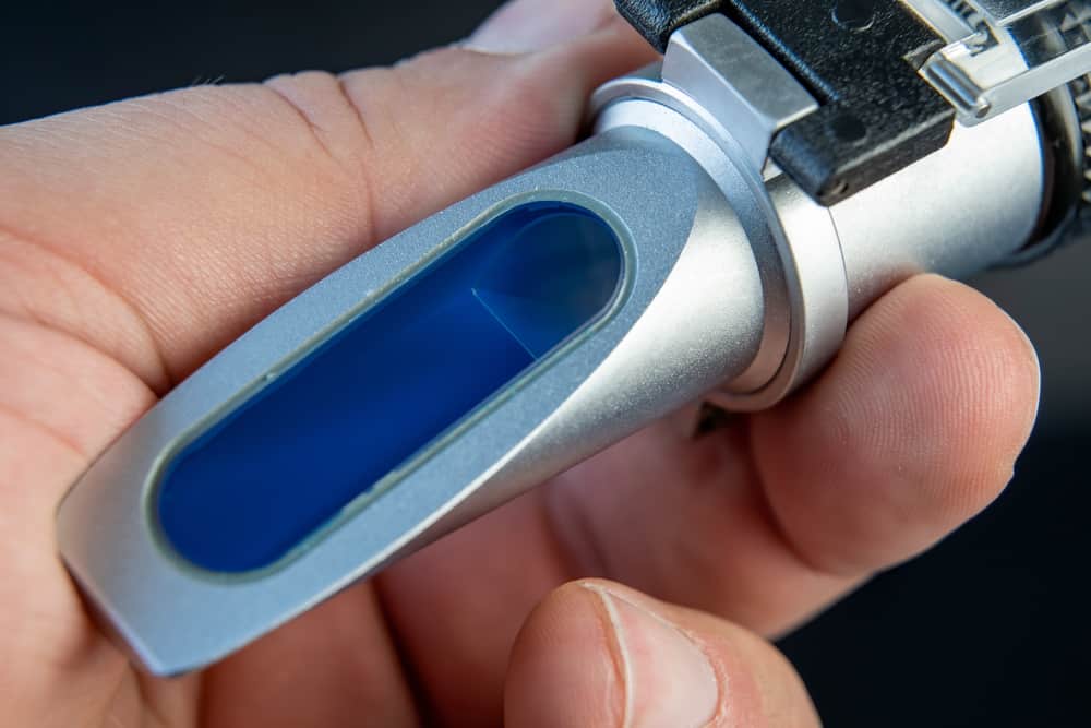 Hand holding refractometer for microscope when analyzing refractometer microscopes by application