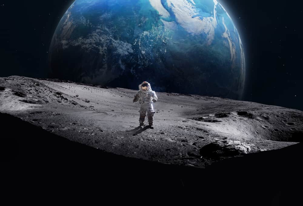 Astronaut walking on surface of moon with Earth in the background