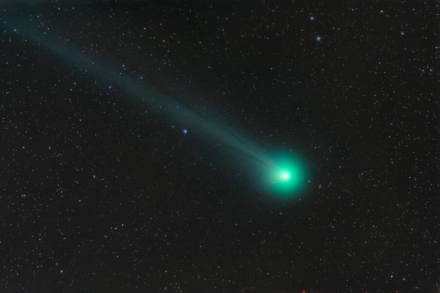 Green comet streaking through black star-filled sky