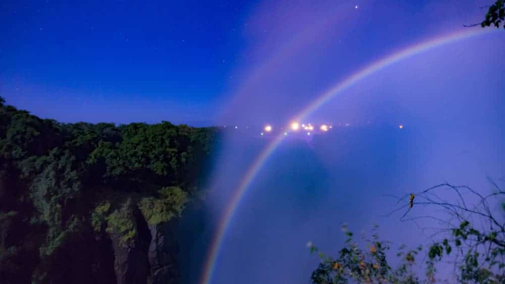 Lunar rainbow moonbow in fog at edge of cliff