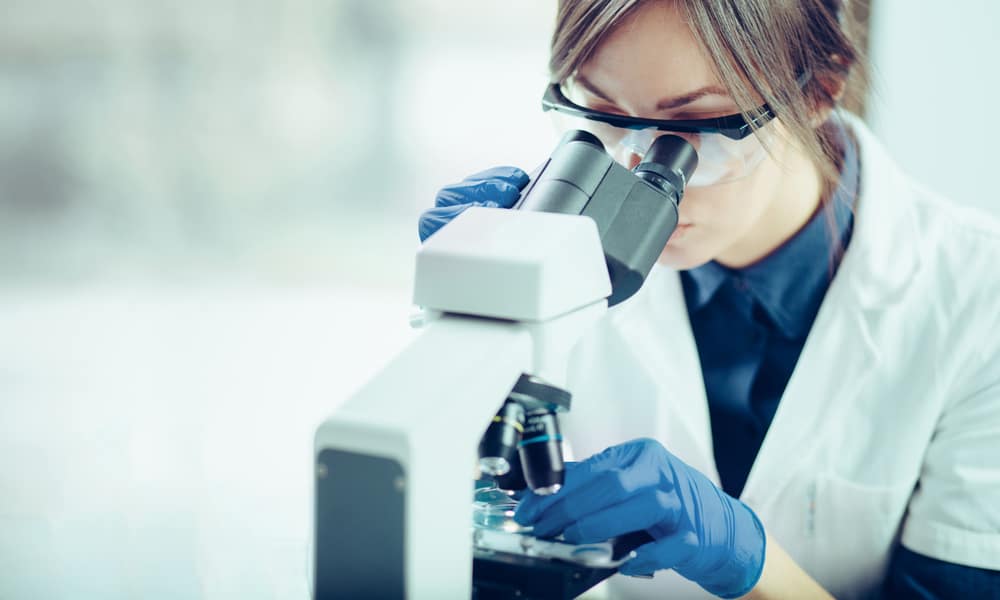 Young-female-scientist-using-phase-contrast-microscope-to-study-samples